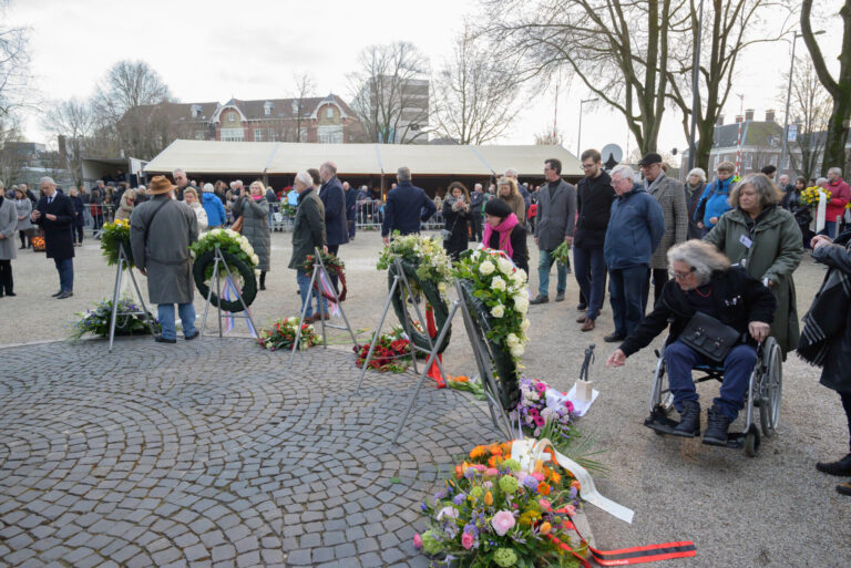 Mensen die bloemen leggen bij de herdenking van de Februaristaking